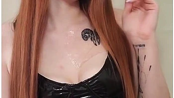 Smoking Redhead With Bright Makeup In A Black Leather Dress