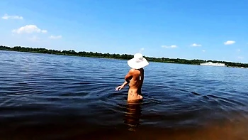 Rubia nudista muestra tatuajes sola en el río